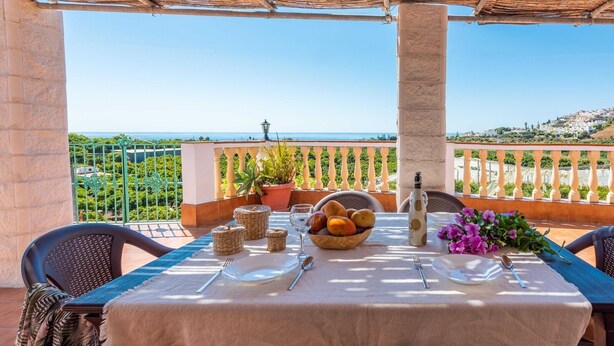 Une table dressée pour deux personnes, avec vue sur la mer et les collines.