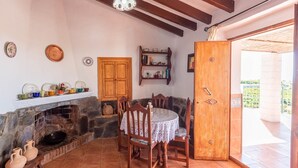 Un coin repas chaleureux avec une cheminée en pierre, des meubles en bois et une vue sur l’extérieur.