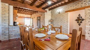 A dining area with a wooden table set for four, surrounded by brick walls and wooden beams.