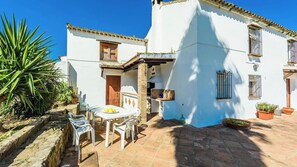 A white building with a patio area, including a table with chairs and a small garden. - Casa del Tigre Gaucín by Ruralidays (Málaga)