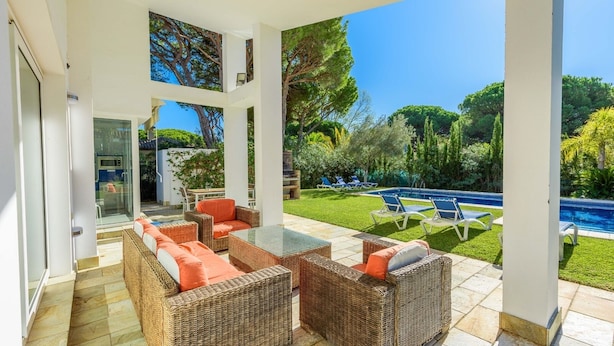 A covered patio with wicker furniture and a glass table, overlooking a pool and lush greenery. - El Cenador Conil de la Frontera by Ruralidays (Cádiz)