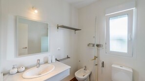 Une salle de bain moderne avec un grand miroir, un lavabo, un bidet et des toilettes.