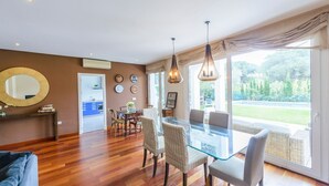 A modern dining area with a glass table and chairs, a large mirror, and a view of the garden through large windows. - El Cenador Conil de la Frontera by Ruralidays (Cádiz)