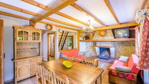 A cozy living room with a stone fireplace, wooden furniture, and a television. - El Rincón de Cazorla La Iruela by Ruralidays (Jaén)