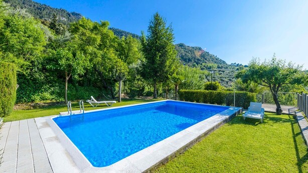 A rectangular swimming pool with a white edge, surrounded by a well-maintained lawn and trees. - El Rincón de Cazorla La Iruela by Ruralidays (Jaén)