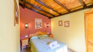 A bedroom with a wooden ceiling, a bed with a green and white bedspread, two wall-mounted lamps, and two framed pictures on the wall. - El Rincón de Cazorla La Iruela by Ruralidays (Jaén)
