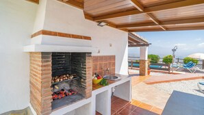 Cocina exterior con parrilla de ladrillo, un lavamanos y vista al mar.