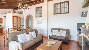 A cozy living room with two sofas, a wooden coffee table, and a fireplace. - Lagar El Mirador Almáchar by Ruralidays (Málaga)