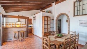 Un comedor con una mesa de madera, sillas y una cocina al fondo.