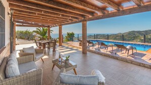 Un’area esterna riparata con mobili in vimini, una piscina e vista sul mare.