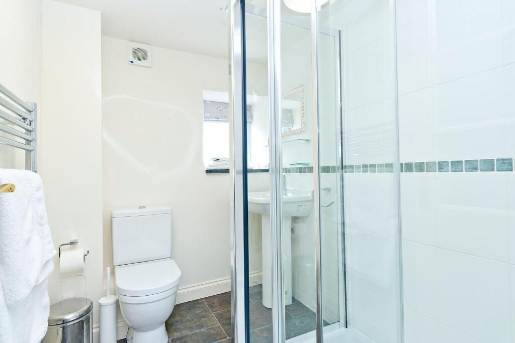 A modern bathroom with a glass-enclosed shower, a toilet, and a sink.
