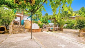 A residential area with a stone staircase leading to a house, a large pot, and a palm tree.