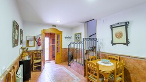 A hallway with a wooden door, a dining area with a table and chairs, and a staircase. - Arados Priego de Córdoba by Ruralidays (Córdoba)