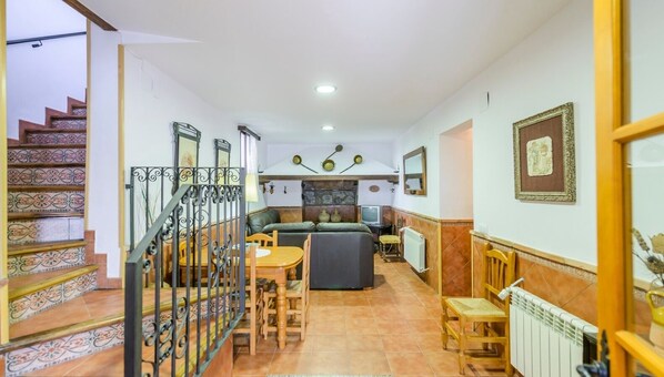 Uma sala de estar espaçosa com escada, sofá, mesa de jantar e televisão.