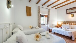 Een hotelkamer met twee bedden, een raam met gordijnen, een houten plafond en een nachtkastje met een lamp.