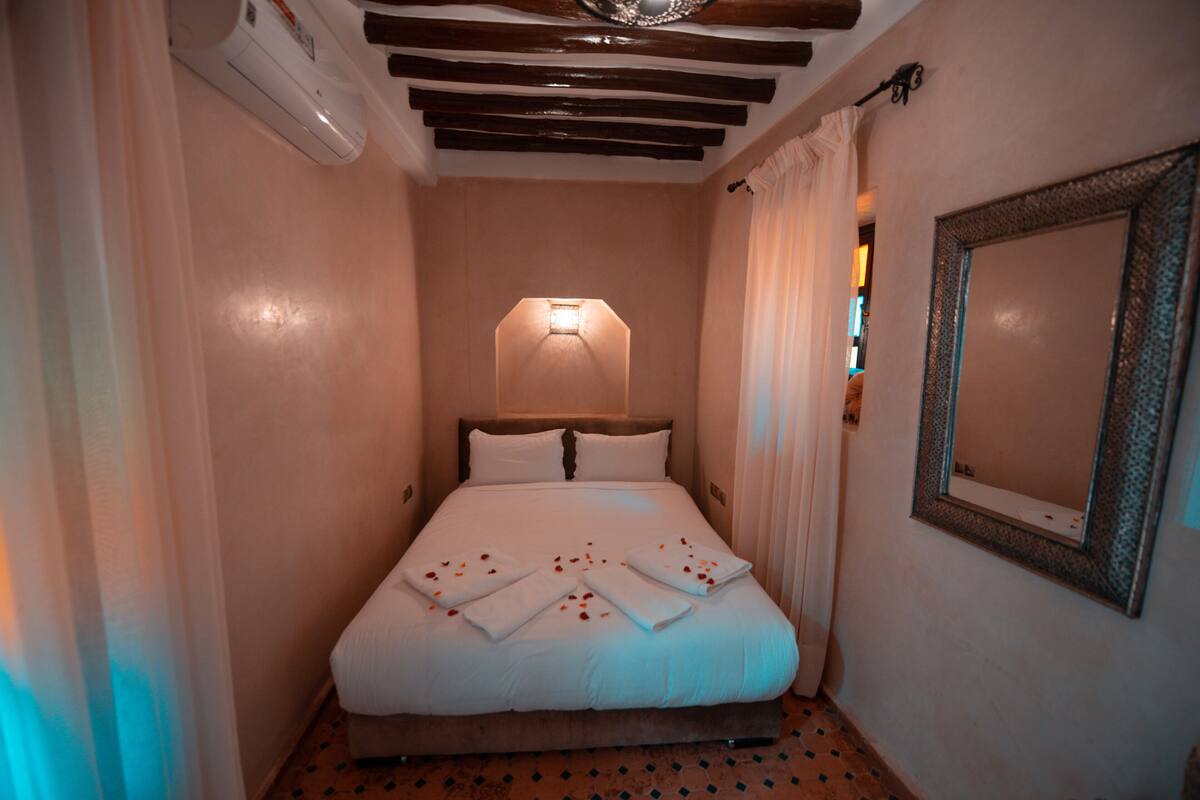 Una habitación de hotel con una cama, un espejo en la pared y una lámpara en el techo.