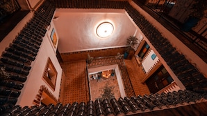 Un escalier en colimaçon avec un luminaire central, entouré de murs recouverts de carreaux décoratifs et d’une rambarde en métal.