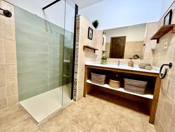 A modern bathroom with a glass shower enclosure, a sink with a wooden vanity, and a mirror above it.