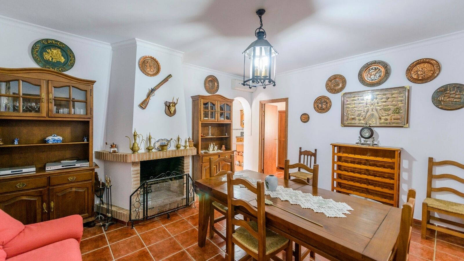 Un comedor con una mesa y sillas de madera, una chimenea y una colección de platos decorativos en las paredes.