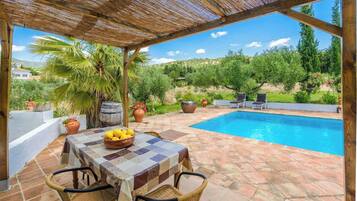 Zona junto a la piscina con mesa, sillas y vistas a una pileta.