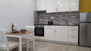 Una cocina moderna con armarios blancos, un horno negro y un refrigerador de acero inoxidable.