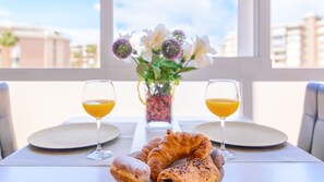 Une table mise pour le petit-déjeuner avec des croissants, du jus d’orange et un vase rempli de fleurs.
