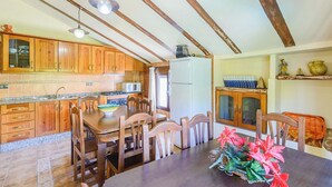 A kitchen with wooden cabinets, a dining table with chairs, and a refrigerator. - Casa Rural Pelijas Fontanar by Ruralidays (Jaén)