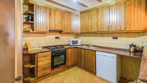 A kitchen with wooden cabinets, a gas stove, a microwave, and a dishwasher. - Casa Rural Pelijas Fontanar by Ruralidays (Jaén)