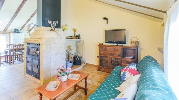 A living room with a fireplace, a television, a sofa, and a dining area. - Casa Rural Pelijas Fontanar by Ruralidays (Jaén)