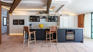 Una cocina moderna con dos taburetes de bar, encimera de mármol y un botellero.