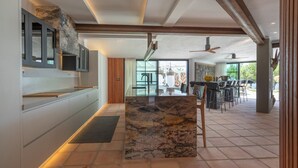 Una cocina moderna con una isla de mármol, electrodomésticos integrados y un comedor con mobiliario para exteriores.
