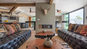 Una sala moderna con sofás de cuero, una mesa de centro y una chimenea de piedra.