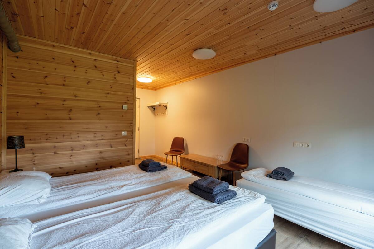Une chambre avec deux lits, un bureau, deux chaises et une lampe.