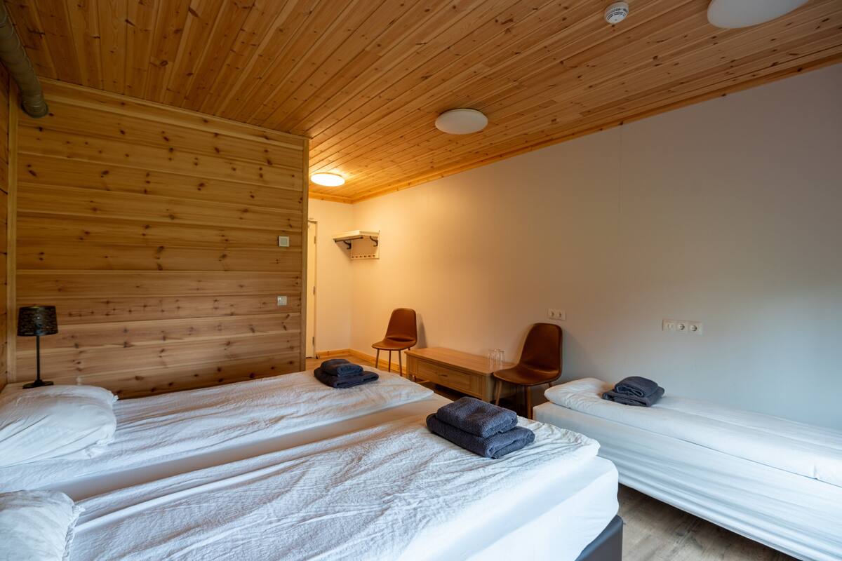 A room with two beds, a desk, two chairs, and a lamp.
