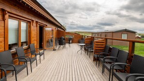 A wooden deck with outdoor seating and a view of the surrounding landscape. - Glaðheimar Guesthouse (Blönduós)