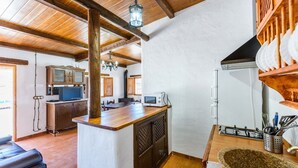Eine Küche mit Holzbalken, einer zentralen Kochinsel und einem Essbereich mit Tisch und Stühlen.
