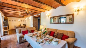 A dining area with a table set for a meal, a sofa with red cushions, and a brick wall in the background.