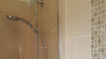 Eine Dusche mit Glastür und einem weißen Handtuchhalter.