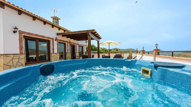 A hot tub area with a pool, outdoor seating, and a building with a tiled roof and stone walls.