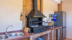 A kitchen with a brick wall, a black oven, a stainless steel sink, and a refrigerator. - Huerta Alejo Alozaina by Ruralidays (Málaga)