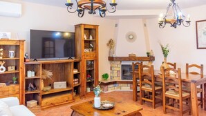 A cozy living room with a fireplace, wooden furniture, and a TV. - Huerta Alejo Alozaina by Ruralidays (Málaga)