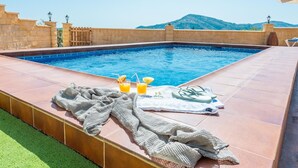 Una piscina amb una tovallola, xancletes i begudes al voltant de la vora.