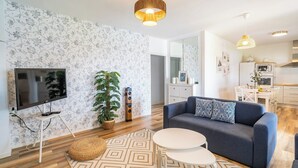 Uma sala de estar moderna com televisão de tela plana, um sofá, uma mesa de centro e uma planta em vaso.