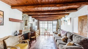 A cozy living room with a stone fireplace, wooden ceiling beams, a sofa, and a television.
