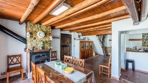 A rustic kitchen with a stone wall, wooden beams, and a fireplace.