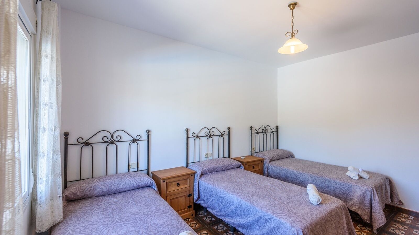A room with three single beds, each with a wooden nightstand.