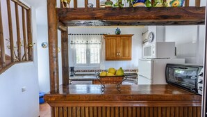 A kitchen with wooden countertops, a microwave, a toaster, and a basket of fruits. - Cortijo Los Naranjos Frigiliana by Ruralidays (Málaga)