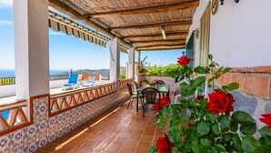A terrace with a view of the sea, a table with chairs, and red roses. - Cortijo Los Naranjos Frigiliana by Ruralidays (Málaga)