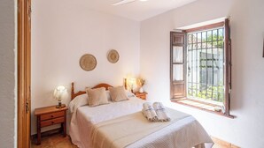 Ein Schlafzimmer mit Bett, Nachttischen, einem Fenster mit Aussicht und zwei Wandbildern.