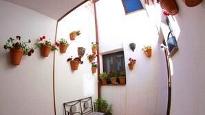 A small patio area with a bench, potted plants, and a window.